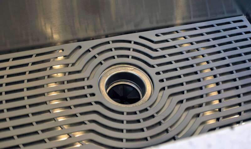 stainless steel kitchen sink detail with grid and disposal