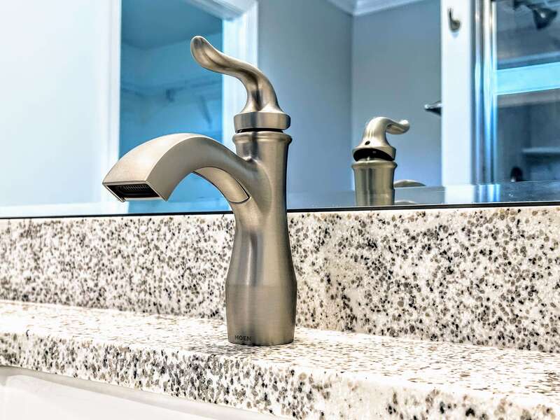 master bath stainless steel lever faucet, mirror, and quartz countertop detail
