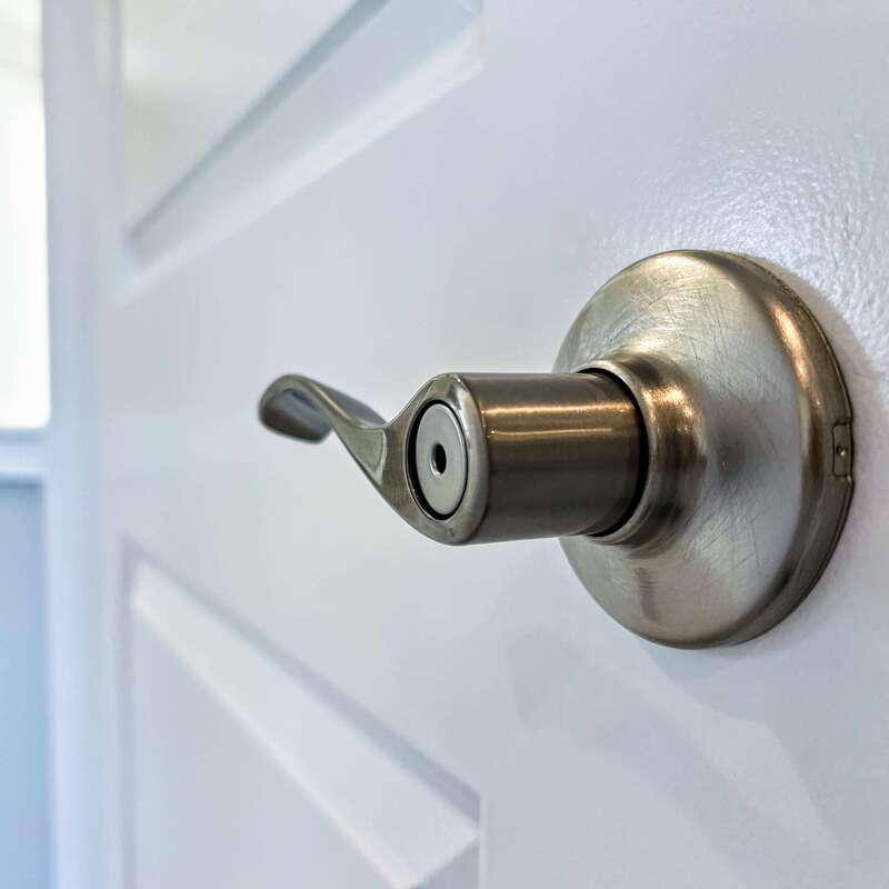 stainless steel levered door handle close-up with white door