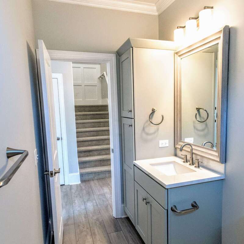 bathroom overall design, including sink, mirror, cabinets, fixtures, grab bar, and stairwell view