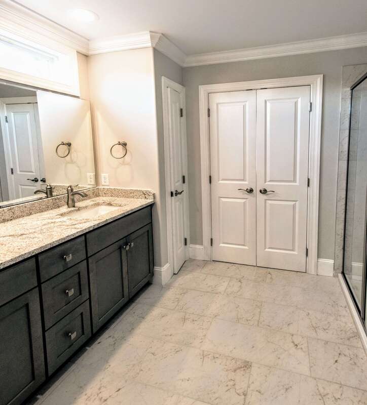 master bathroom with french doors, linen closet, walk-in shower, privacy window, double sinks, and tiled floors